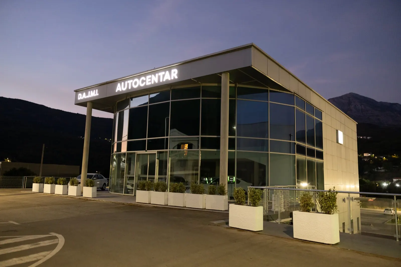 Osvijetljeni natpis D.A.J.M.I. Autocentar u sumrak